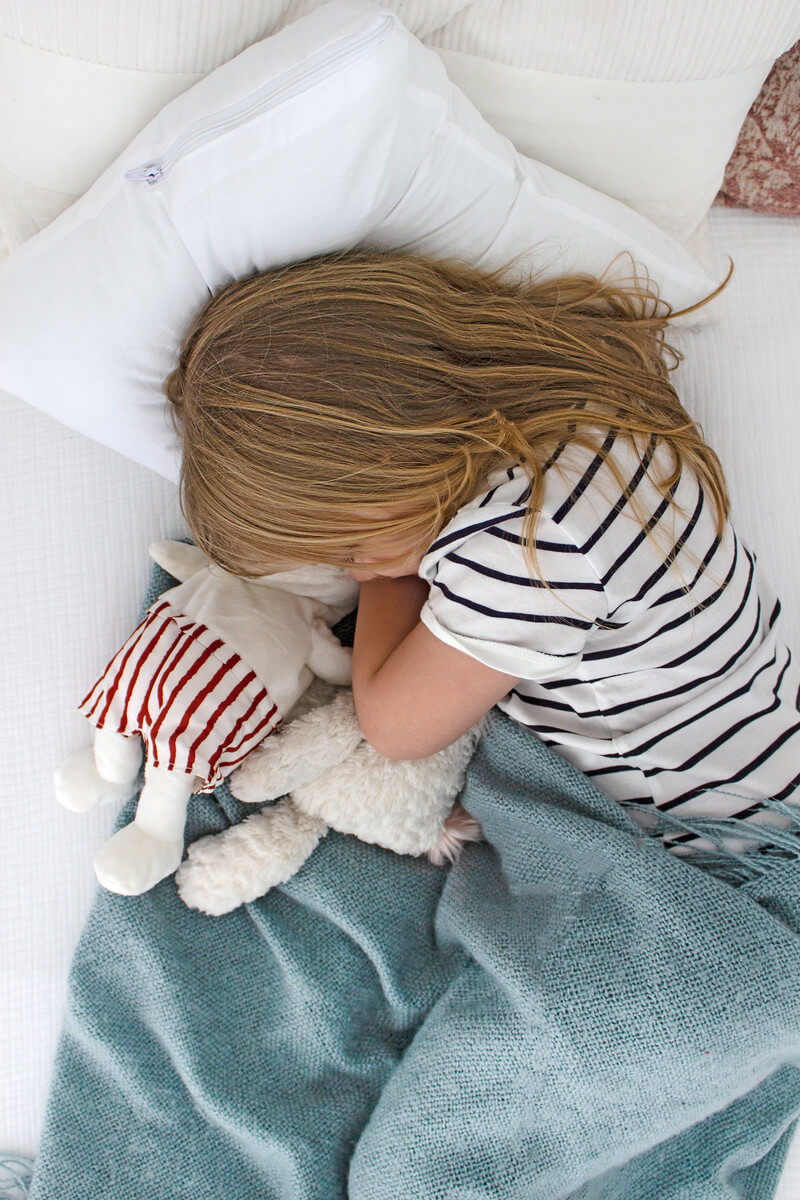 little girl sleeping in bed with blanket and stuffed animal